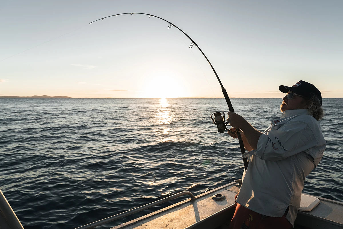 Angler bent into a fish on a Penn Supremacy spin rod at sunrise